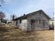 Side exterior view of house, showing aged siding, boarded up windows and dry grassy yard at 3072 Semmes St, East Point, GA 30344