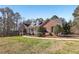 A picturesque view of a red brick home, with mature landscaping and dormer windows at 211 Garden W Walk, Hampton, GA 30228