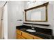 Classic bathroom with a wooden vanity, black granite countertop, and framed mirror at 301 Madison Se Ct, Smyrna, GA 30080