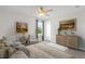 Bright bedroom with a ceiling fan, large bed, wood dresser, two chairs, and art pieces on the walls at 237 Kindness Cir, Mcdonough, GA 30252