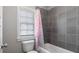 Bathroom featuring gray tiled walls, toilet and tub with pink shower curtain at 1918 Coal Pl, Atlanta, GA 30318