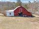 Exterior shot of a classic red barn with white trim and a separate shed attached at 3200 Fence Rd, Dacula, GA 30019