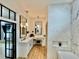 Bright bathroom with white chevron tiled accent wall, wood floors, and a vanity with dual mirrors and pendant lighting at 590 Hood Ave, Fayetteville, GA 30214