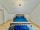 Primary bedroom featuring a plush blue bedspread, tufted bench, statement lighting, and wood floors at 590 Hood Ave, Fayetteville, GA 30214