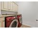 Convenient laundry room with built-in cabinets and modern, red appliances at 4305 Kendall Way, Roswell, GA 30075
