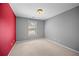 Cozy carpeted bedroom featuring a bright window and contrasting red accent wall at 1094 N Village Dr, Decatur, GA 30032