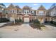 Two-story townhomes feature brick and siding exteriors, individual garages, and professionally landscaped front yards at 1094 N Village Dr, Decatur, GA 30032