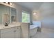 Bright bathroom showcasing a soaking tub, window, and vanity with white cabinetry at 226 Linford Dr, Locust Grove, GA 30248