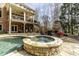 Backyard oasis featuring a stone-clad hot tub, fireplace, covered deck, and mature trees at 5284 Vernon Springs Trl, Sandy Springs, GA 30327