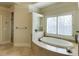 Bright bathroom features a soaking tub with travertine tile surround and plantation shutters at 5284 Vernon Springs Trl, Sandy Springs, GA 30327