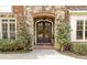 A stone archway surrounds double front doors with manicured bushes and brick walkway at 5284 Vernon Springs Trl, Sandy Springs, GA 30327