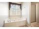 Bathroom featuring a corner soaking tub, a window, and a walk-in shower at 582 Black Forest Run, Douglasville, GA 30134