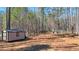 Exterior view of a shed in a wooded backyard, offering outdoor storage space at 582 Black Forest Run, Douglasville, GA 30134