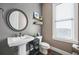 Chic powder room with a pedestal sink, round mirror and natural light at 6415 Berkdale Way, Suwanee, GA 30024