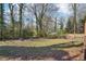 Expansive backyard featuring a fire pit and wooden fence, bordered by mature trees, creating a private outdoor space at 1694 Kenmore Sw St, Atlanta, GA 30311