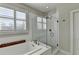 Bright bathroom featuring a soaking tub with shuttered window and glass-enclosed shower at 3601 Ridgeway Rd, Duluth, GA 30096