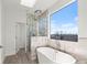 Modern bathroom showcases a soaking tub, glass shower, and large window with views of the surrounding landscape at 145 Hutchinson Ne St, Atlanta, GA 30307