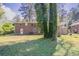 Green backyard with large trees and red brick home under a partially cloudy sky at 1753 Dodson Sw Dr, Atlanta, GA 30311