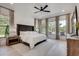 Elegant bedroom featuring a tufted headboard, light hardwood floors, and backyard views at 2497 Sugar Pike Rd, Canton, GA 30115