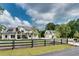 Home's facade is shown with a dark fence across the front yard and a long driveway at 2497 Sugar Pike Rd, Canton, GA 30115