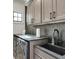 Well-lit laundry room featuring a stainless steel washer and dryer, dark backsplash, and ample cabinet space at 2497 Sugar Pike Rd, Canton, GA 30115