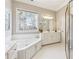 Bright bathroom featuring a soaking tub, white cabinetry and ample storage space at 3999 Treemont Ln, Suwanee, GA 30024