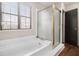 Bathroom featuring tub with glass door, window with blinds, and wood flooring at 9556 River Ct, Jonesboro, GA 30238