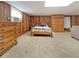 Comfortable bedroom with wood paneled walls, featuring a queen-sized bed and dresser at 3415 Spot Rd, Cumming, GA 30040