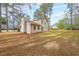 Expansive backyard with mature trees surrounding a home with a stone chimney and sliding glass door at 5065 Hubert Dr, Powder Springs, GA 30127