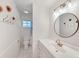 Bright bathroom features white walls, tiled floors, toilet, vanity with modern fixtures, and a round mirror at 7360 Fields Dr, Cumming, GA 30041