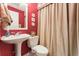 Cozy bathroom featuring a pedestal sink, toilet, and shower with bright red walls at 154 Hunters Trl, Dallas, GA 30157