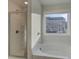 Bright bathroom featuring a separate glass enclosed shower and soaking tub under a large window at 325 Heavenly Hollow Pl, Mcdonough, GA 30253