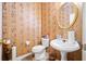 Elegant powder room featuring floral wallpaper, a round mirror, and a white pedestal sink at 6068 Magnolia Rdg, Stone Mountain, GA 30087