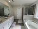 Well-lit bathroom featuring a walk-in shower, a soaking tub, and double sinks with plenty of storage at 4161 Dean Grove Way, Loganville, GA 30052
