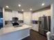 Bright kitchen features stainless steel refrigerator, island with quartz countertops, and white cabinets at 4161 Dean Grove Way, Loganville, GA 30052