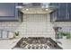 Close-up of the gas range and vent hood with decorative tile backsplash in a modern kitchen at 2755 Turning Leaf Dr, Lawrenceville, GA 30044