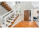 Inviting foyer featuring hardwood floors, a wooden front door, and a staircase with glass and white wood railing at 5930 N Eton Ct, Duluth, GA 30097