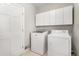 Bright laundry room featuring a washer and dryer, white cabinets, and a door at 5930 N Eton Ct, Duluth, GA 30097