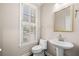 Bright half-bathroom featuring a pedestal sink, toilet, and shuttered window at 1545 Heritage Trl, Roswell, GA 30075