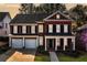 Lovely red brick two-story home featuring a covered porch, black shutters, and an attached two-car garage at 1545 Heritage Trl, Roswell, GA 30075