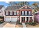 Beautiful red brick two-story home featuring a covered porch, black shutters, and an attached two-car garage at 1545 Heritage Trl, Roswell, GA 30075