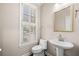 Elegant half-bathroom featuring a pedestal sink, decorative mirror, and natural light from the window at 1545 Heritage Trl, Roswell, GA 30075