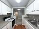 Galley kitchen featuring white cabinets, wood flooring, modern appliances, and a view of the hallway at 3020 Wingate Way, Sandy Springs, GA 30350