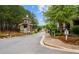 Landscaped community entrance with stone guardhouse, flower beds, and manicured greenery along a paved road at 320 Gray Shingle Ln, Woodstock, GA 30189