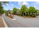 A scenic community entrance is framed by lush trees, flowers, and decorative landscaping under a partly cloudy sky at 320 Gray Shingle Ln, Woodstock, GA 30189