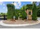 A stone wall covered in ivy marks the entrance to the village, framed by manicured shrubbery and brick walkways at 320 Gray Shingle Ln, Woodstock, GA 30189