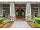 Stunning entrance with stone columns, stone facade, arched wood door, and manicured landscaping at 320 Gray Shingle Ln, Woodstock, GA 30189