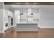 Modern kitchen with white cabinets, a gray island, hardwood flooring, and a view of the fireplace and living area at 320 Gray Shingle Ln, Woodstock, GA 30189