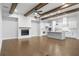 Open-concept living room with a fireplace, hardwood floors, wood beams, and a view of the modern kitchen at 320 Gray Shingle Ln, Woodstock, GA 30189