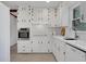 Bright white kitchen features white cabinets, tiled backsplash, stainless oven, modern appliances, and neutral tile flooring at 4169 Cedar Valley Ln, Conley, GA 30288